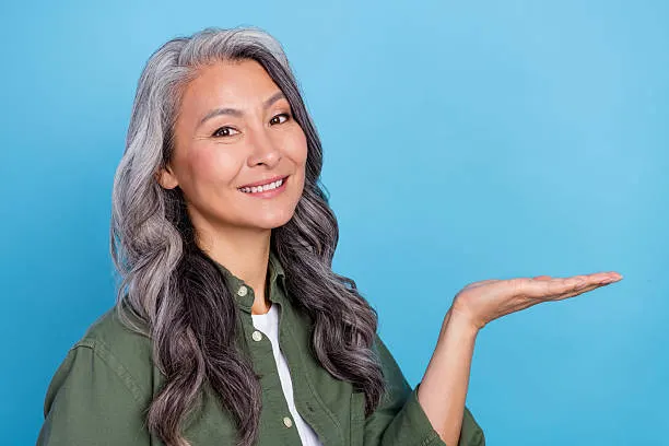 Photo of cute elder grey hairdo lady hold empty space wear green shirt isolated on blue color background.